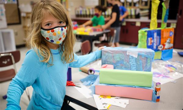 Student holds up a castle made out of recycled materials